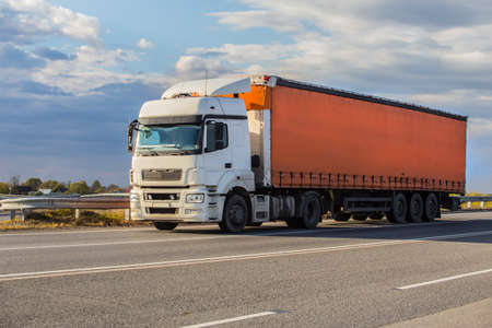 Truck semi-trailer moves along the highway at sunriseの写真素材