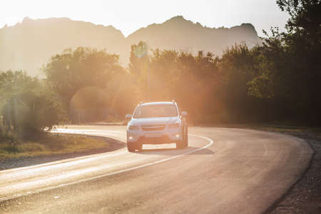 car rides on a winding road in the mountains on a sunny day