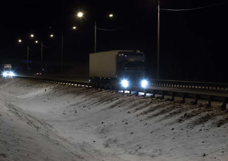 Trucks is moving along the winter road at nightの写真素材