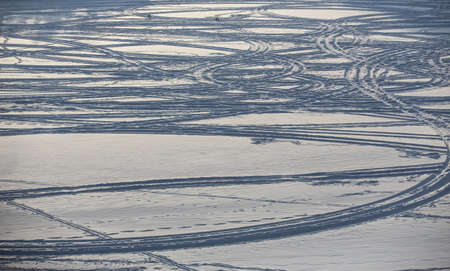 Traces of skis and snowmobiles on the surface of a winter snow lakeの写真素材