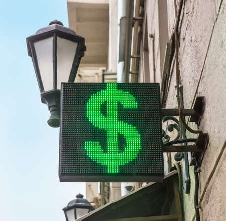 Dollar symbol on a diode panel on a building wall