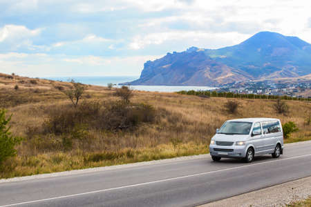 Minibus moves along the road along the sea in the highlandsの写真素材