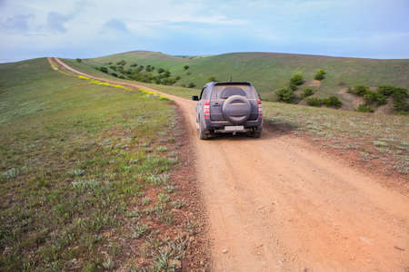 Off-road Car Moves along a dirt mountain road to the sea