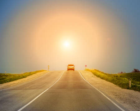 Ð¡ar moves on a country highway in the sun