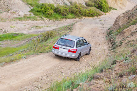 car goes down the mountain dirt road to the sandy beachの写真素材