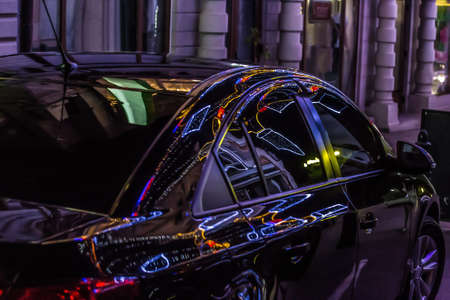 car at night in the city in reflections of neon advertisingの写真素材