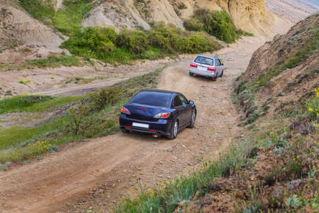 Cars goes down the mountain dirt road to the sandy beachの写真素材