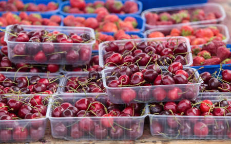 Berries of ripe cherries in plastic trays on the counterの写真素材
