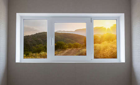Window view of a beautiful mountain landscape with trees and field