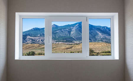 Window view of a beautiful mountain landscape with trees and field