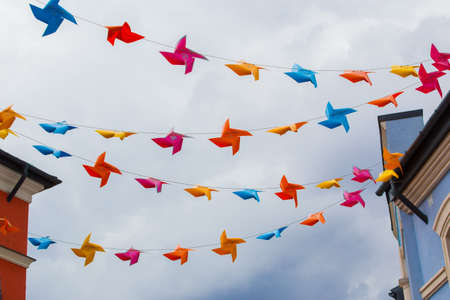 Festive street decoration under the roofs of buildings on the ropes colored decorative plastic elementsの写真素材