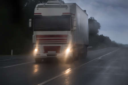 truck moving in rain and fog on a country road