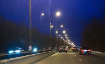 Car traffic in winter on a suburban highway at night.