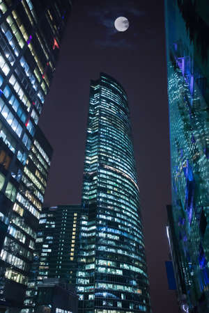 Modern office buildings skyscrapers with light in the windows on a moonlit nightの写真素材