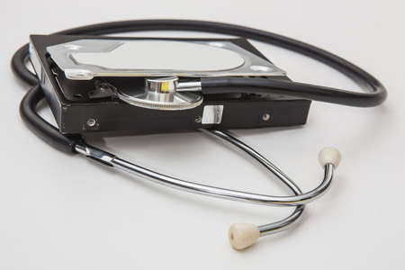 Open computer hard drive and phonendoscope on a white background. Conceptual diagnostics of computer...