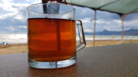 Mug with tea on a table under a canopy on the seashore in summerの写真素材