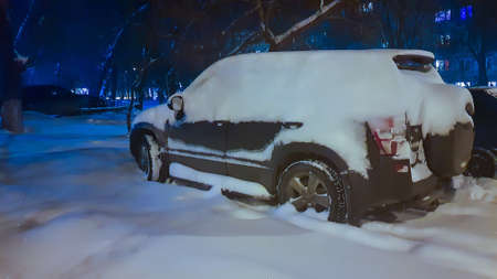 Car in the parking lot in the yard in winter under snow at night.の写真素材