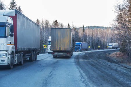 Trucks move on a suburban highway in the winter in the forestの写真素材