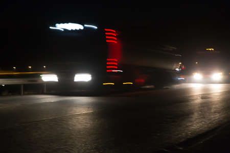Fuel trucks carry gas at night on a suburban highway. Motion blur.