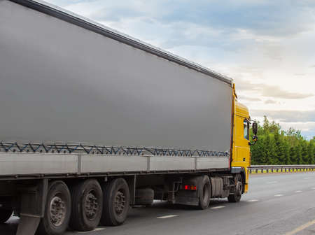 Truck semi-trailer moves along the highway at sunrise