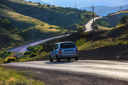 car moves on a mountain road under a cloudy sky