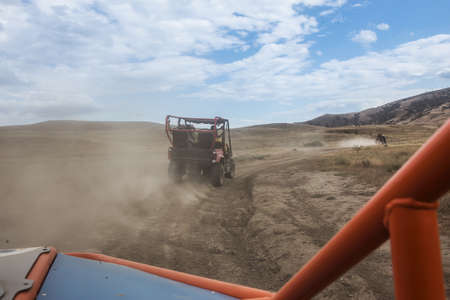 Buggy moves on a dirt dusty road in a mountainous area