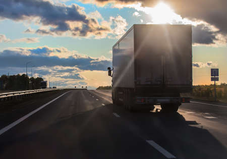 truck moves along a suburban highway lit by the sun.の写真素材