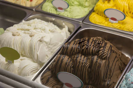 Ice cream of different colors in metal trays in a cafeの写真素材