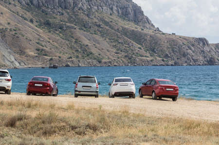 Cars by the bay on the sea in front of the mountains. Weekends in nature.の写真素材