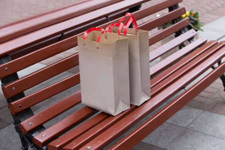 Two paper shopping bags with shopping on a street benchの写真素材