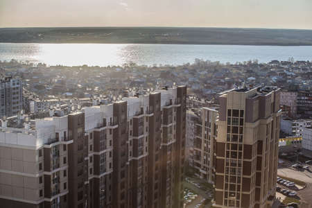 High-rise residential buildings and cottages by the river at sunset