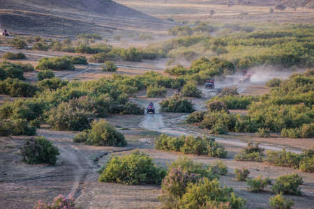 ATVs ride on a dirt road in a beautiful area