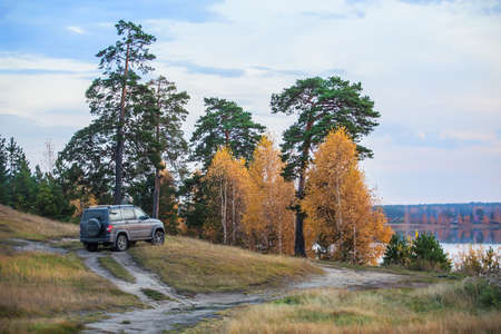 SUV on the shore of a beautiful lake in autumn