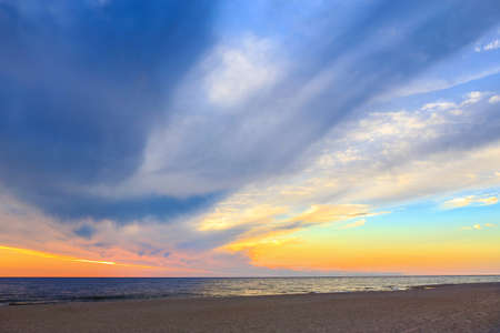 Beautiful Cloudy Sky at Dawn over the Sea at the Sandy Shoreの写真素材