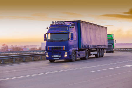 Trucks Moving On Country Road At Sunsetの写真素材