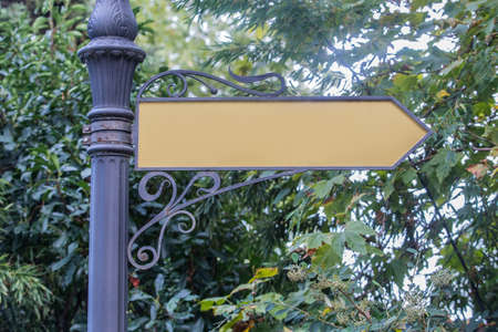 Arrow pointer attached to a pillar against a background of treesの写真素材