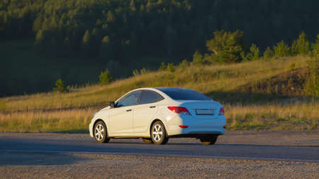 Car Drives along the Country Highway at Sunset along the forest