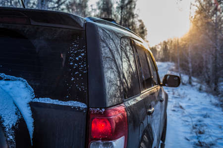 SUV moves in winter along a snow-covered country road in the forestの写真素材