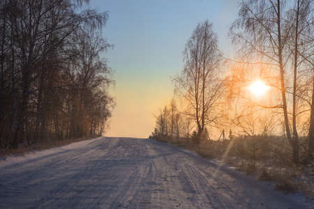 Winter snowy road in the morning at sunset landscapeの写真素材