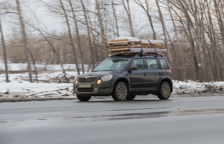 Car transports cardboard boxes on top trunk on winter roadの写真素材