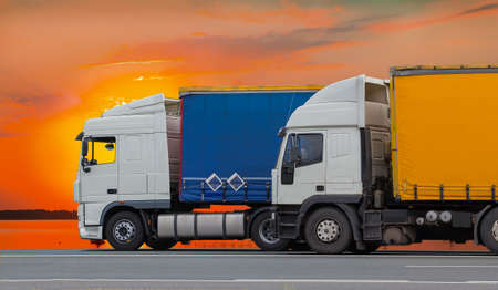 Trucks move along the highway against the background of a red sunset skyの写真素材