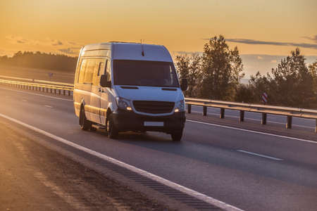 minibus moves along suburban highway at sunrise