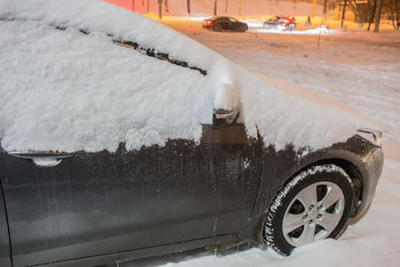 Car on a winter night under the snow close-up