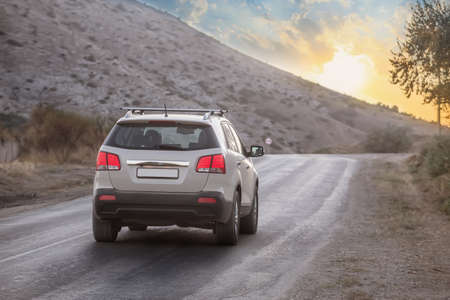 SUV moves along a mountain country road at sunrise
