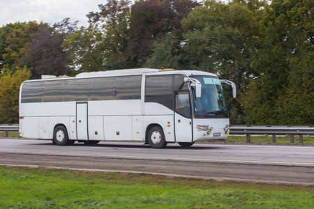 Tourist bus moves on a country road in summerの写真素材