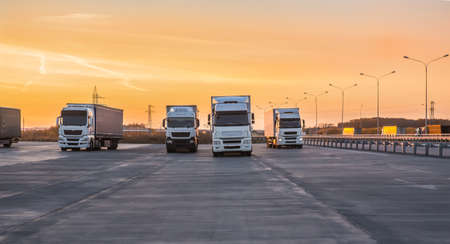 Trucks in a parking lot on a suburban highway at dawnの写真素材