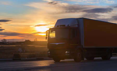 Truck Goes on Highway in evening on sunsetの写真素材