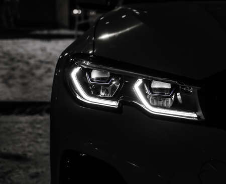 LED headlight of a black car at night close-upの写真素材