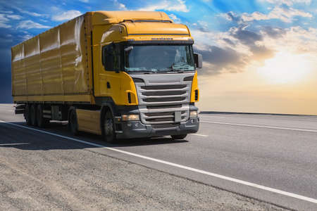 Truck moves on a country highway at sunsetの写真素材