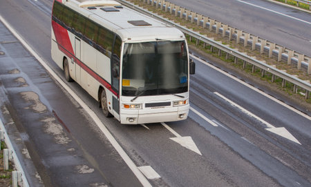 Bus moves along the suburban highway on summer dayの写真素材